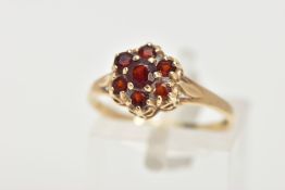 A 9CT GOLD GARNET CLUSTER RING, flower cluster set with seven circular cut garnets, prong set,