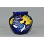 A SMALL MOORCROFT POTTERY BALUSTER VASE, decorated with tube lined blue Clematis pattern on a dark