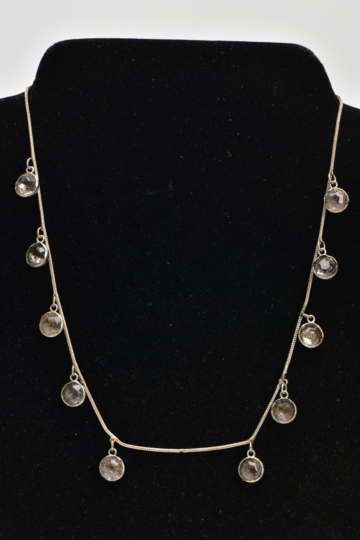 A WHITE METAL AND PASTE NECKLACE, designed as ten old cut paste stones each in a bezel domed back