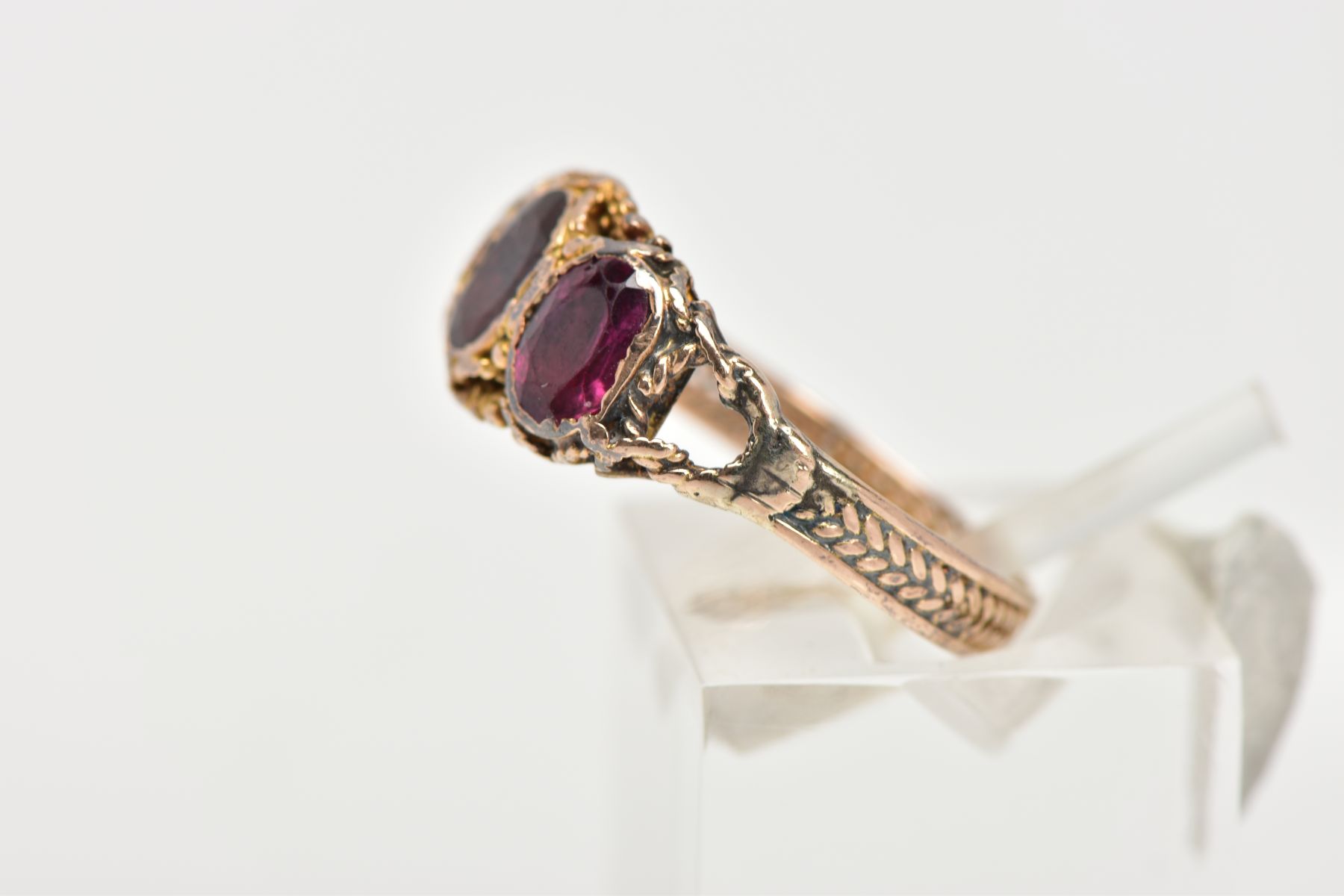 A THREE STONE GARNET RING, three oval cut garnets set within a rope twist surround leading on to the - Image 2 of 4