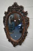 A HARDWOOD FRAMED OVAL WALL MIRROR, with carved open foliate detail, 68cm x 113cm