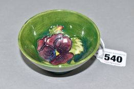A SMALL MOORCROFT POTTERY FOOTED BOWL, decorated with tubelined purple Pansy pattern on a green/