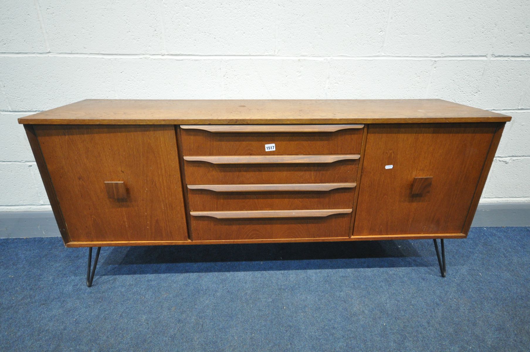 A MID CENTURY TEAK SIDEBOARD with two cupboard doors flanking four drawers on later metal hairpin