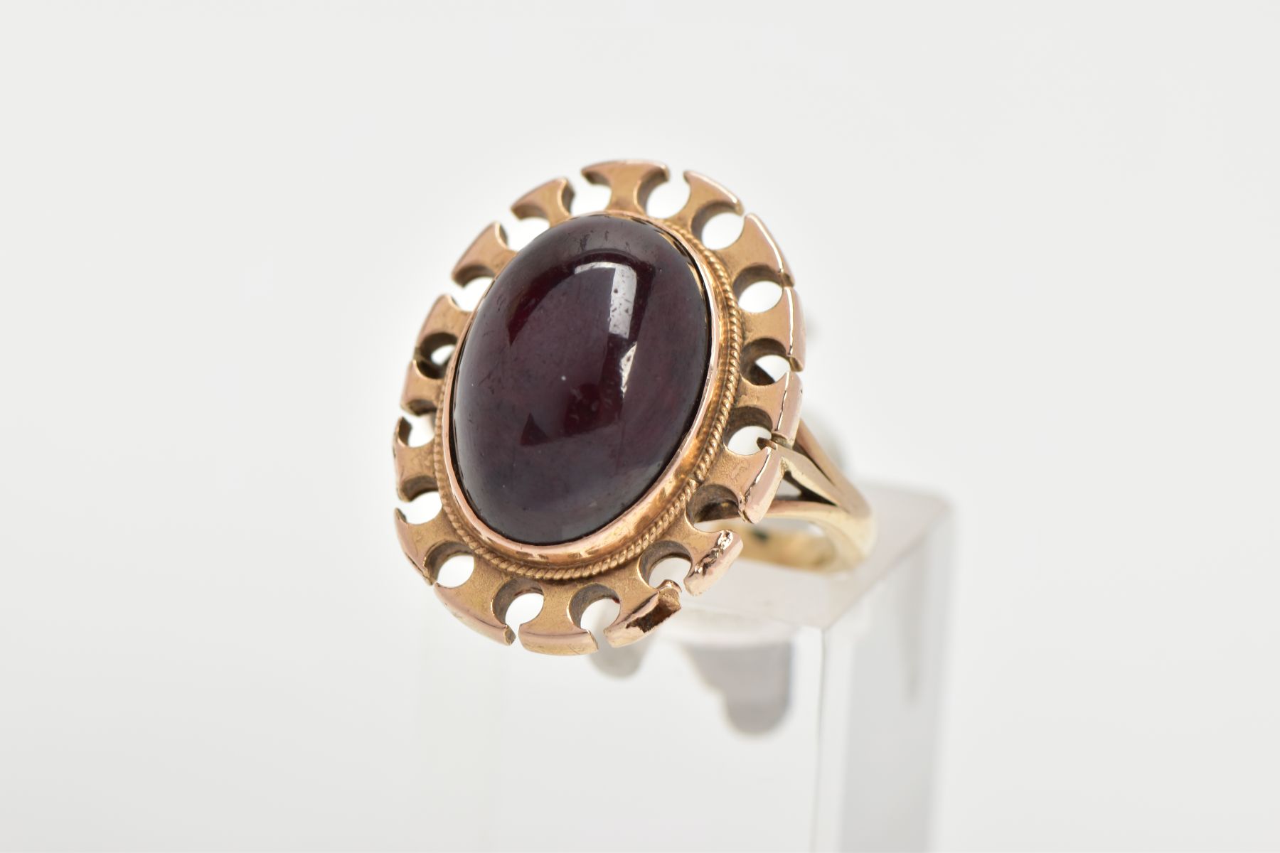 A YELLOW METAL GARNET RING, of an oval form set with an oval garnet cabochon, bezel set with a