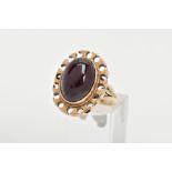 A YELLOW METAL GARNET RING, of an oval form set with an oval garnet cabochon, bezel set with a