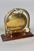 A BRASS AND OAK TABLE TOP DINNER GONG, a marriage, with Edwardian frame and later 'Lucky Pixie'