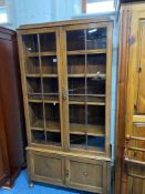 AN OAK GLAZED TWO DOOR BOOKCASE, with four adjustable shelves, above double panelled cupboard doors,