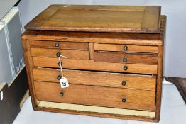 A VINTAGE OAK TOOL CHEST, carrying handle to the top, slide off front revealing an arrangement of