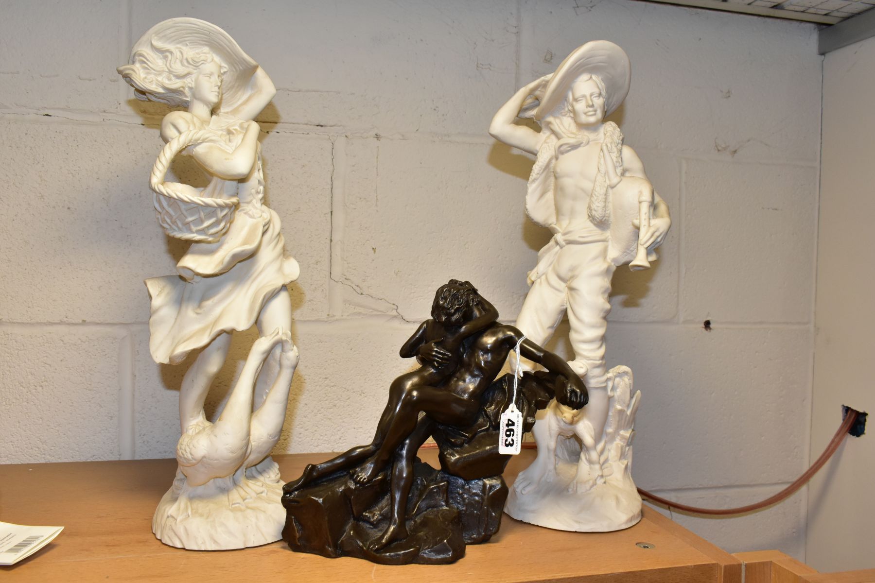 A PAIR OF WHITE RESIN FIGURES OF A MAN AND A WOMAN AND A HEREDITIES BRONZED RESIN FIGURE GROUP '