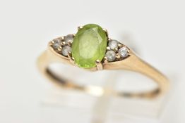 A 9CT GOLD PERIDOT RING, an oval cut peridot, accented with six circular cut cubic zirconia, in a