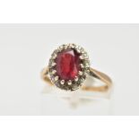 A GARNET AND DIAMOND CLUSTER RING, an oval cut almandine garnet surrounded with a halo of round
