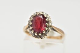 A GARNET AND DIAMOND CLUSTER RING, an oval cut almandine garnet surrounded with a halo of round