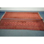 TWO RED WOOLLEN TEKKE CARPET RUNNERS, 298cm x 84cm