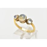 A YELLOW METAL MOONSTONE RING, designed with a central circular cut moonstone and flanked with two
