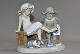 A LLADRO FIGURE GROUP 'TRY THIS ONE', NO. 5361, a boy and girl trying on shoes, designed by Regino