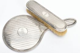 A SILVER VANITY MIRROR AND CLOTHES BRUSH, the mirror of a round form, engine turned design and