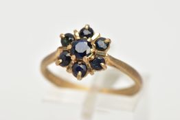 A 9CT GOLD SAPPHIRE CLUSTER RING, seven circular cut sapphires prong set in a floral design, leading