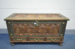 AN EASTERN HEAVILY CARVED HARDWOOD BLANKET BOX with brass adornments, internal candle box and