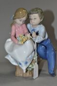 A LLADRO FIGURE GROUP 'JUST A LITTLE KISS', NO. 5701, a boy and girl sitting on a tree stump,