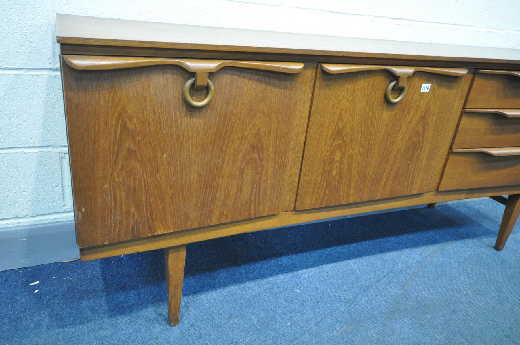 A MID CENTURY BEAUTILITY TEAK CONCAVE SIDEBOARD, with three graduated drawers, the top drawer with - Image 2 of 3