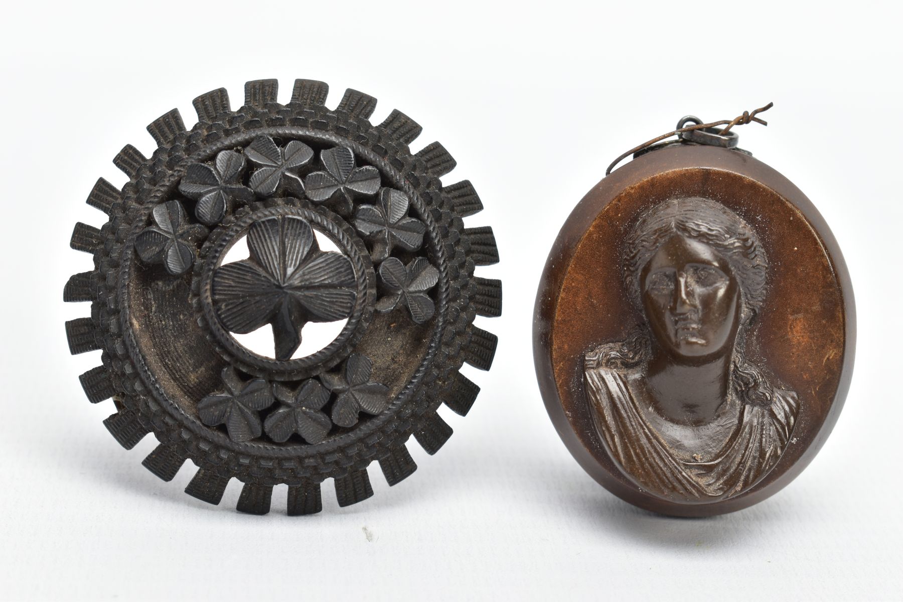 A JET BROOCH AND A VULCANITE PENDANT, the jet brooch of a circular form, decorated with carved