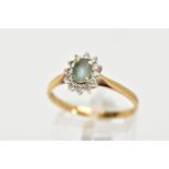 AN 18CT GOLD GEM SET CLUSTER RING, of an oval form, centring on an oval cut aquamarine, within a