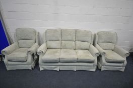 A GREEN FLORAL UPHOLSTERED THREE PIECE LOUNGE SUITE, comprising a three seater settee and a pair