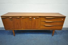 A MID CENTURY BEAUTILITY TEAK CONCAVE SIDEBOARD, with three graduated drawers, the top drawer with