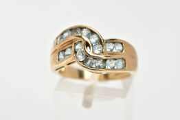 AN AQUAMARINE DRESS RING, sixteen circular cut aquamarine stones channel set in a double row cross