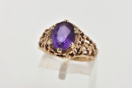 AN AMETHYST DRESS RING, designed with a six claw set, oval cut amethyst, textured openwork