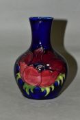 A MOORCROFT POTTERY BOTTLE SHAPED VASE DECORATED WITH RED/MAUVE ANEMONE ON A BLUE GROUND,