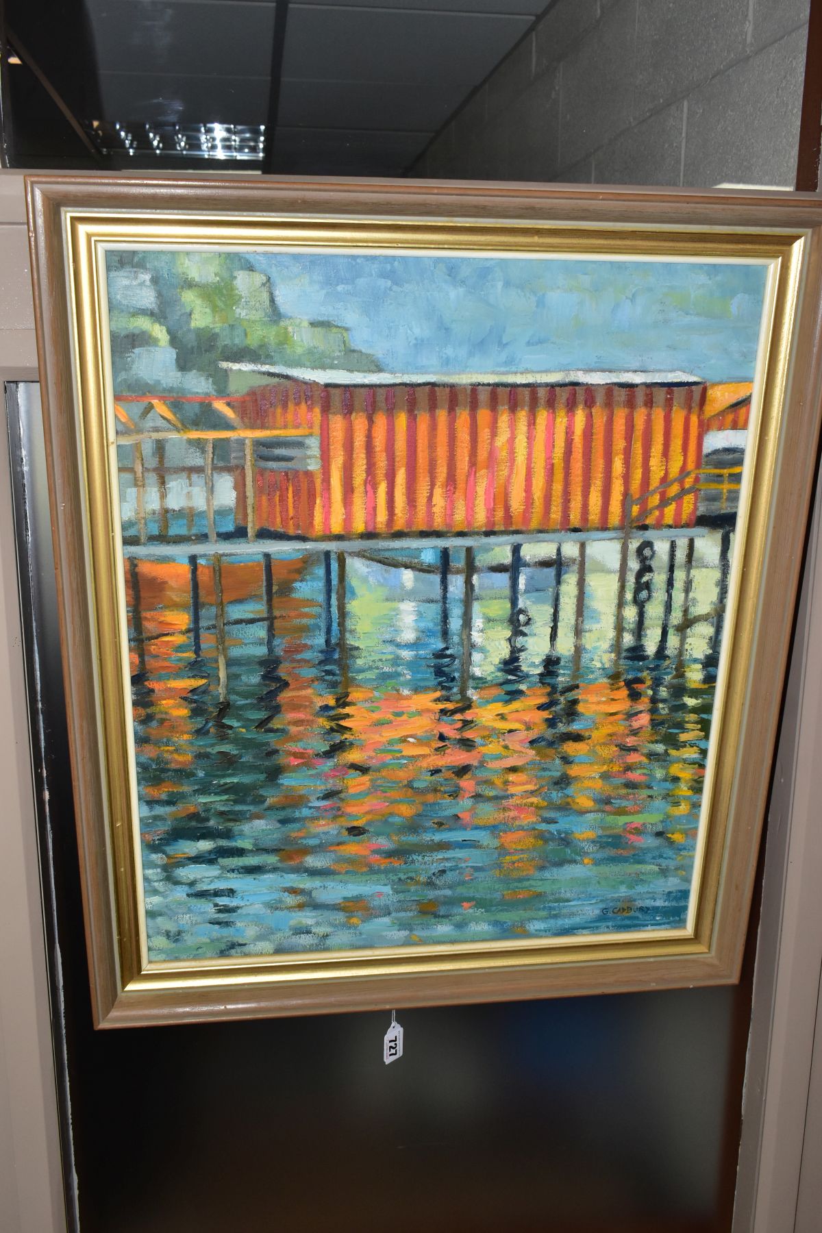 G CADBURY (20TH CENTURY), A COLOURFUL BUILDING ON A PIER OVER WATER, signed bottom right, oil on