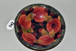 A MOORCROFT POTTERY SHALLOW BOWL DECORTATED IN THE POMEGRANATE DESIGN ON A MOTTLED BLUE / GREEN