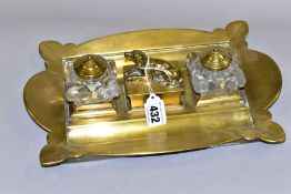 A BRASS TWIN INKWELL DESK STAND, having scalloped edges, two square glass inkwells with brass covers