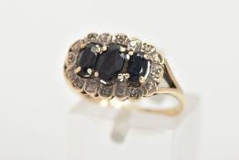 A 9CT GOLD SAPPHIRE RING, three oval cut blue sapphires prong set in a surround of eight round