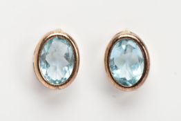 A PAIR OF GEM SET EARRINGS, oval cut blue stones assessed at topaz set in a yellow metal basket