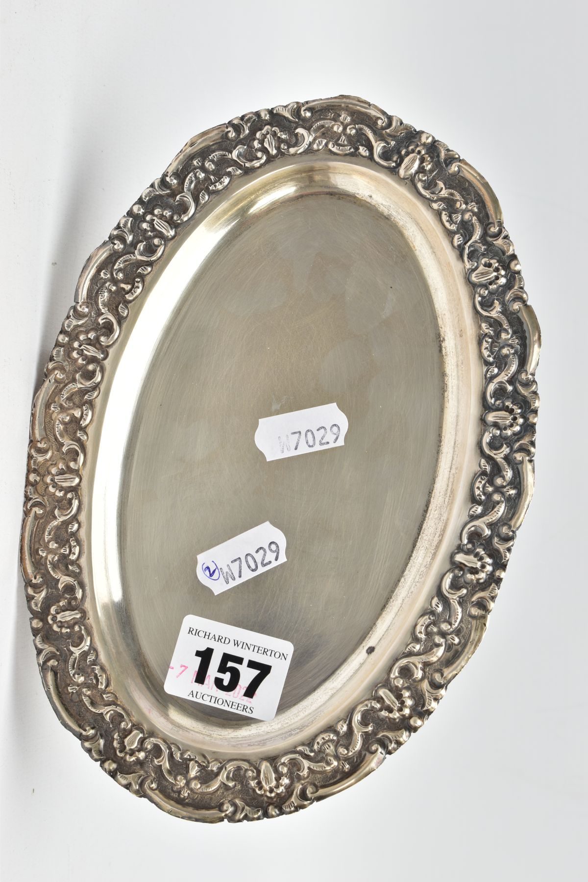 AN OVAL WHITE METAL TRAY, embossed foliate rim, engraved to the reverse of the base 'Presented to