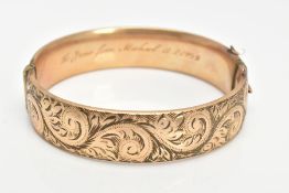 A 9CT GOLD METAL CORE BANGLE, half with a foliate scroll detail, fitted with a push pin clasp,