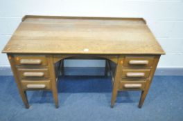 AN EARLY TO MID 20TH CENTURY OAK SLOPPED TOP DESK, with six drawers, on square tapered legs, width