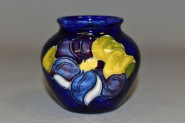 A SMALL MOORCROFT POTTERY BALUSTER VASE, decorated with tube lined blue Clematis pattern on a dark