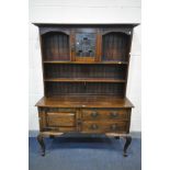 AN ARTS AND CRAFTS OAK DRESSER, two plate rack sections flanking a central lead glazed cupboard, the