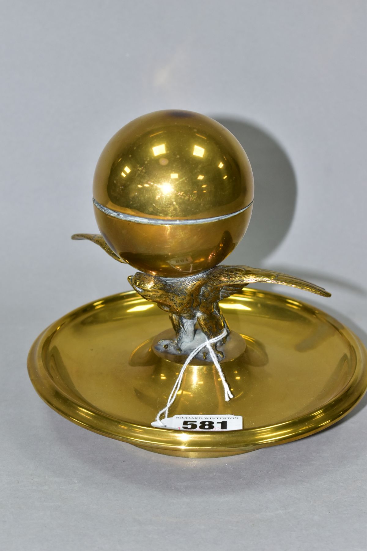 A BRASS INKSTAND IN THE FORM OF AN EAGLE AND ORB, incorrect glass liner, liner retaining ring is