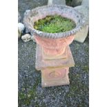 A MODERN COMPOSITE TERRACOTTA COLOURED GARDEN PLANTER ON STAND, the planter has foliate detailing to