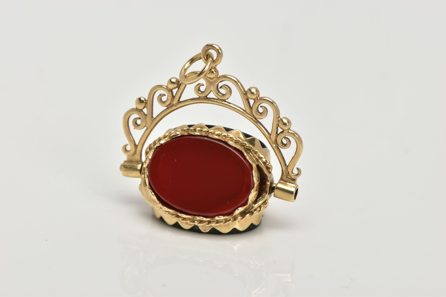 A 9CT GOLD SWIVEL FOB, set with oval cut onyx, carnelian and bloodstone panels, openwork scroll
