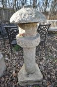 A GRANITE GARDEN LANTERN, in five pieces, rustically carved with a windowed candle holder and rustic