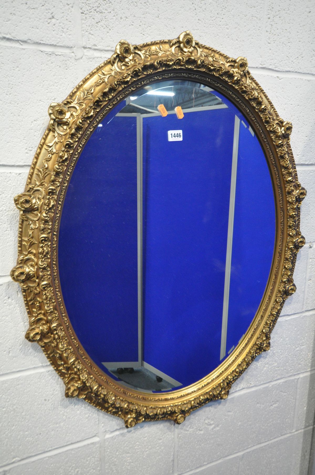 A LATE 20TH CENTURY GILT FRAMED OVAL WALL MIRROR, with foliate and rose head decorations, 97cm x