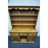 A PINE DRESSER, with a later three tier plate rack top, over three drawers and cupboard doors, width