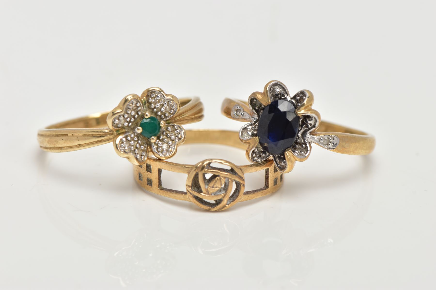 THREE 9CT GOLD RINGS, the first set with an oval cut blue sapphire, within a floral surround set