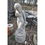A LARGE COMPOSITE GARDEN FIGURE IN THE FORM OF SCANTILY CLAD GRECIAN LADY leaning against rocks