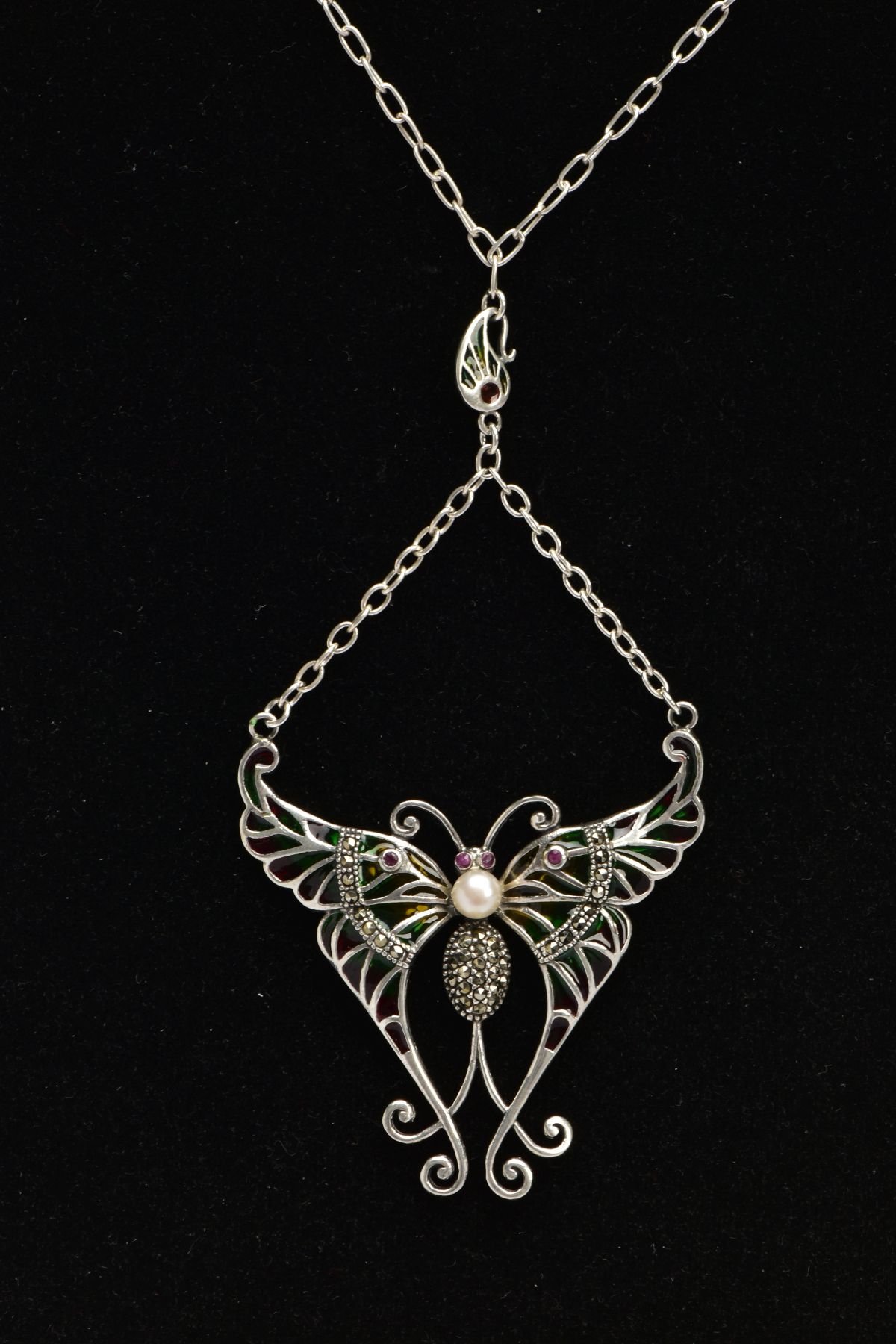 A PLIQUE A' JOUR BUTTERFLY NECKLACE, a white metal butterfly set with four circular cut rubies, a